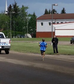 student running across street towards teacher and building